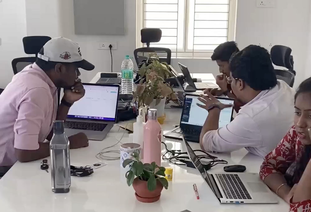 Team collaboration session with designers and developers working together on laptops around a table